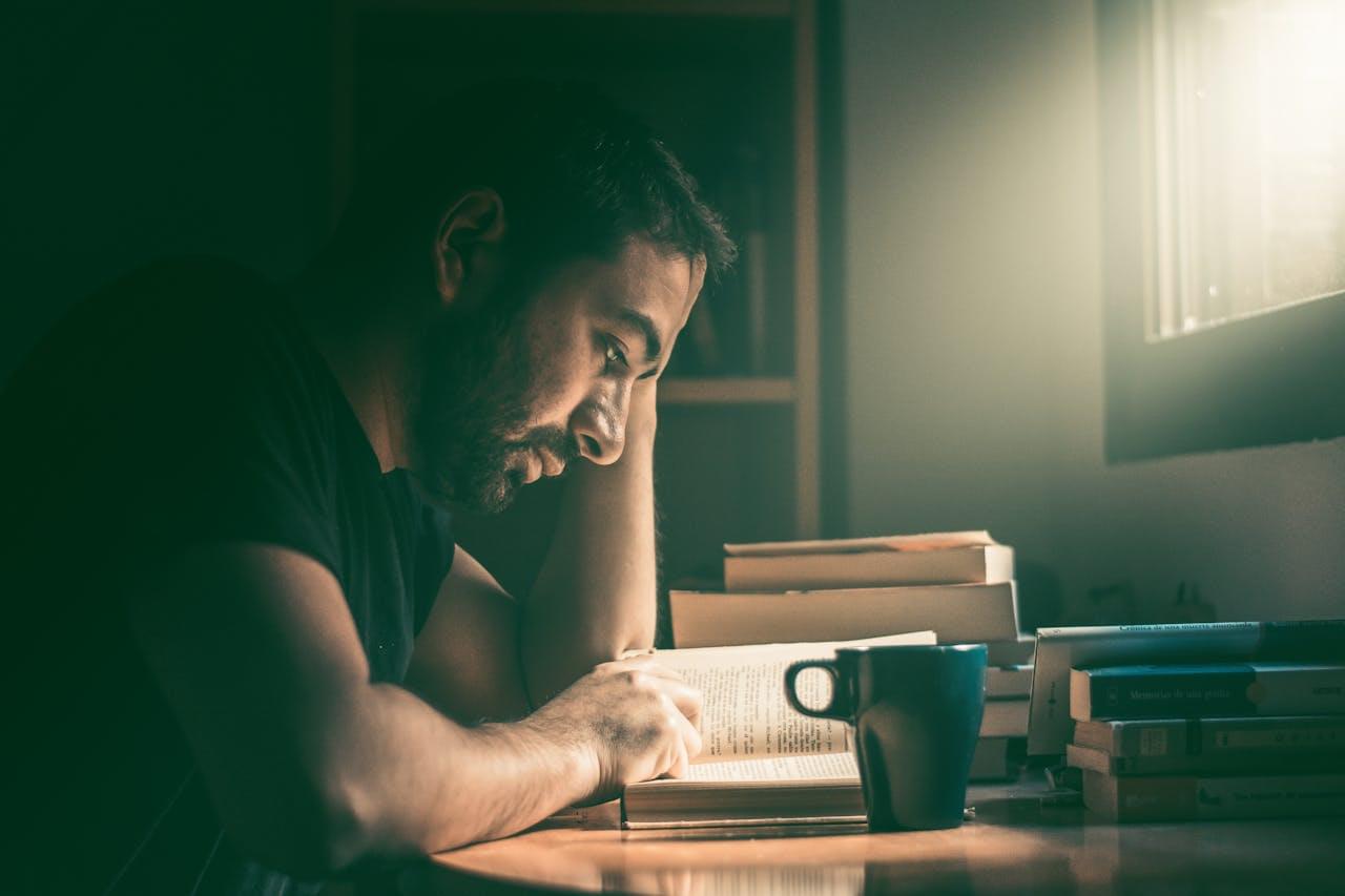 Человек читает книгу за столом